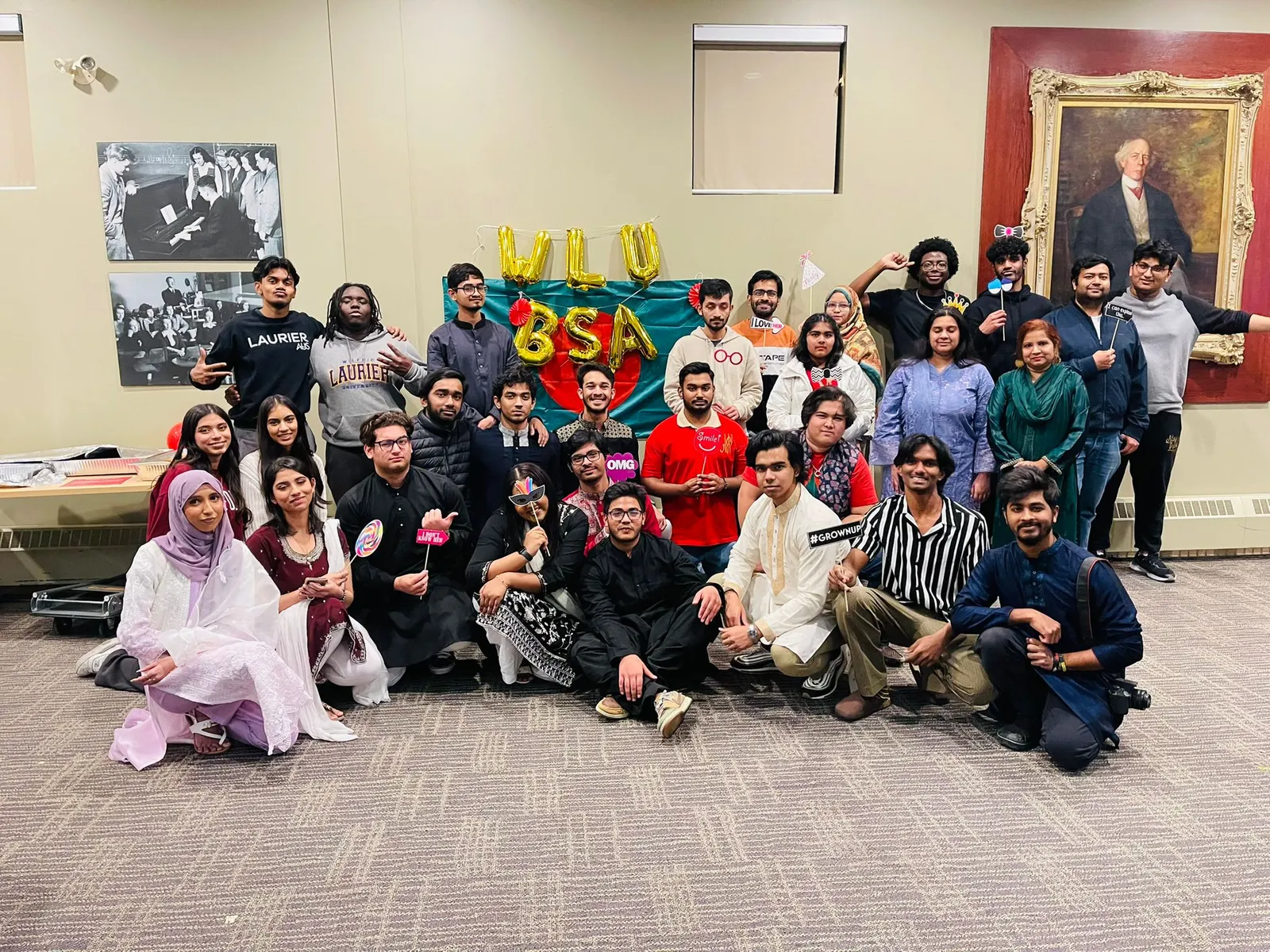 A large group photo in front of a WLU BSA balloon sign and the Bangladesh flag at Freedom Fest 2024.