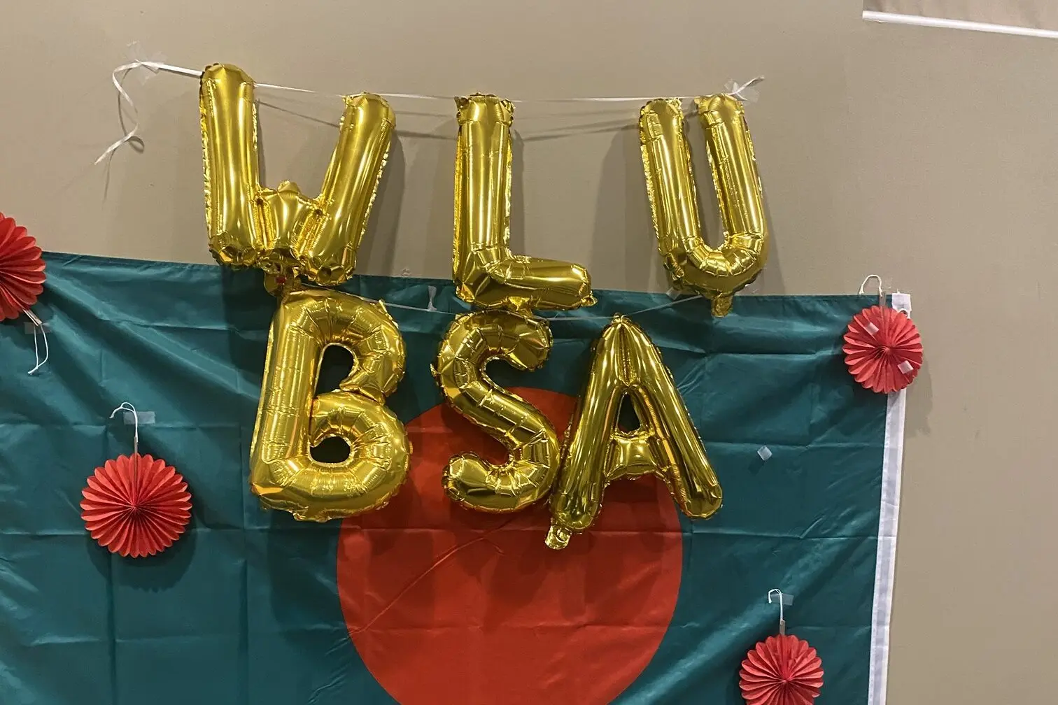 Gold balloon letters spelling WLU BSA over a Bangladesh flag with red paper fans.